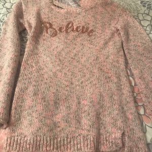 A sweater that has the letters believe.